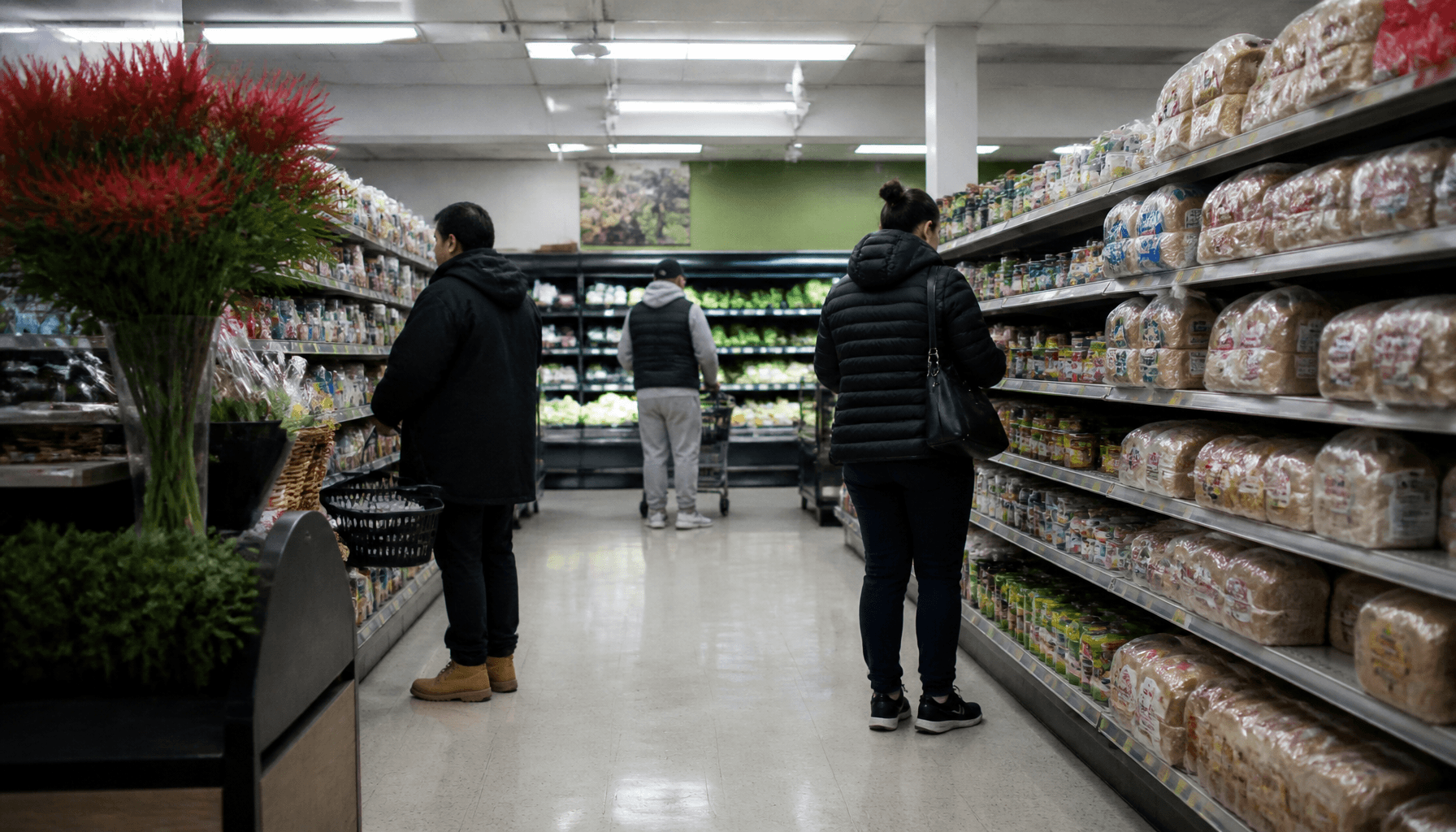 Shoppers in a New Zealand supermarket aisle checking prices amid rising living costs