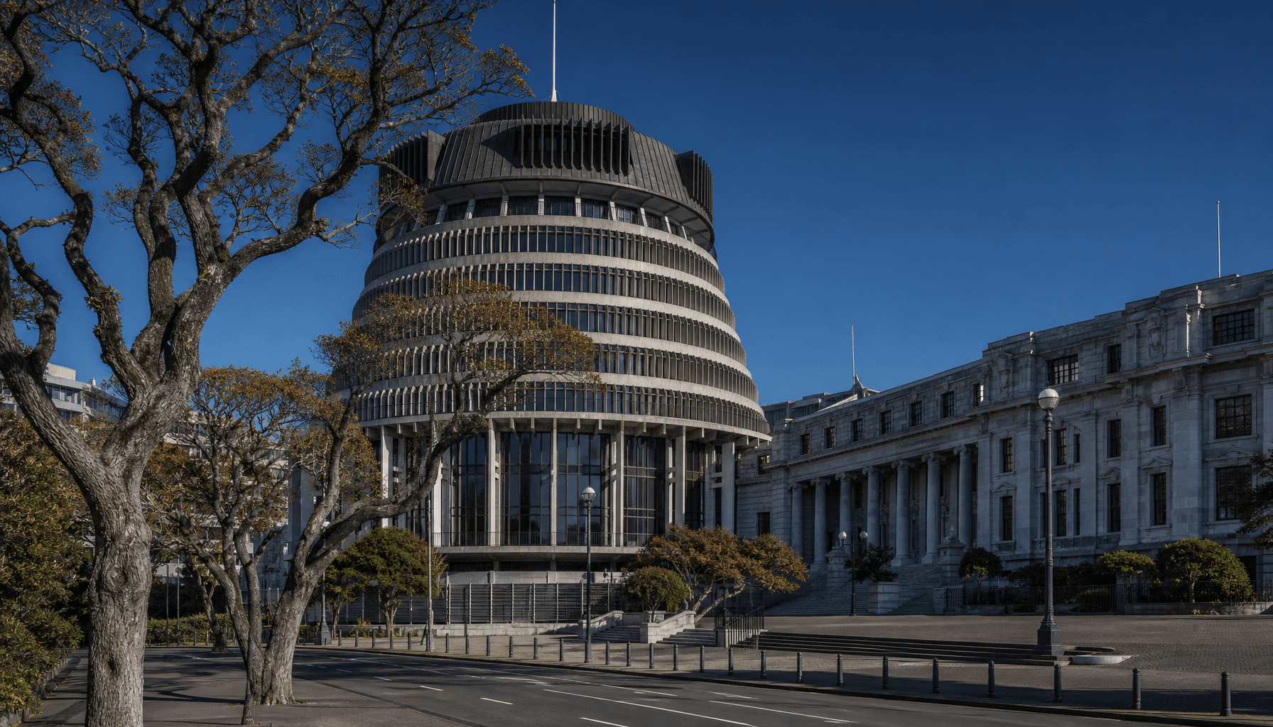The Beehive and Parliament Buildings in Wellington under clear blue skies, empty forecourt, late-autumn morning light