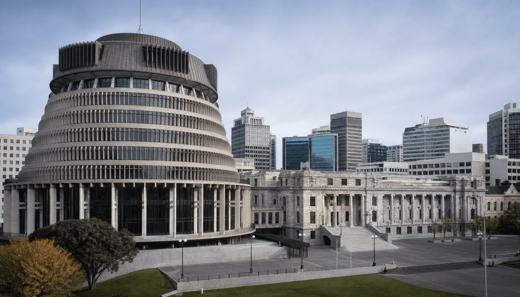 Wellington's Beehive and Parliament House in cool morning light, framed against Lambton Quay office towers