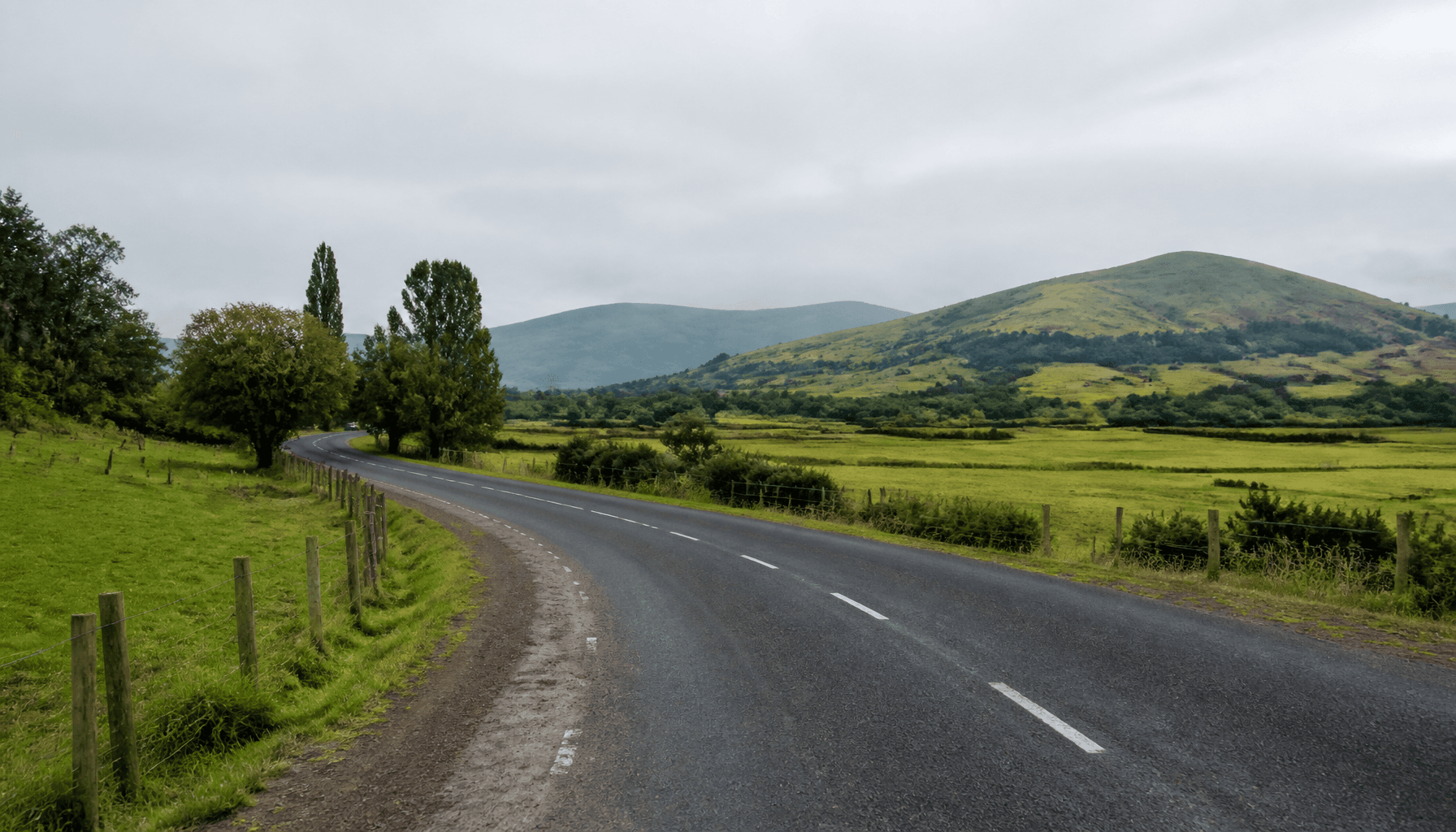 Rural New Zealand local road through farmland under overcast sky