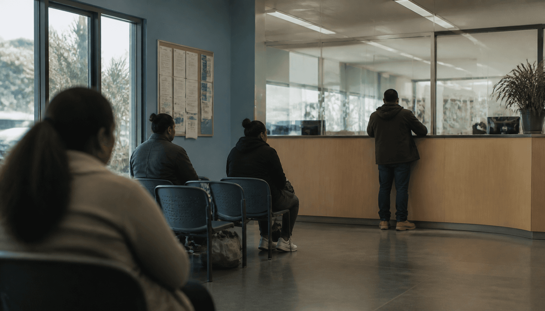 South Auckland employment office interior with adults waiting at a timber counter, natural light, no faces visible